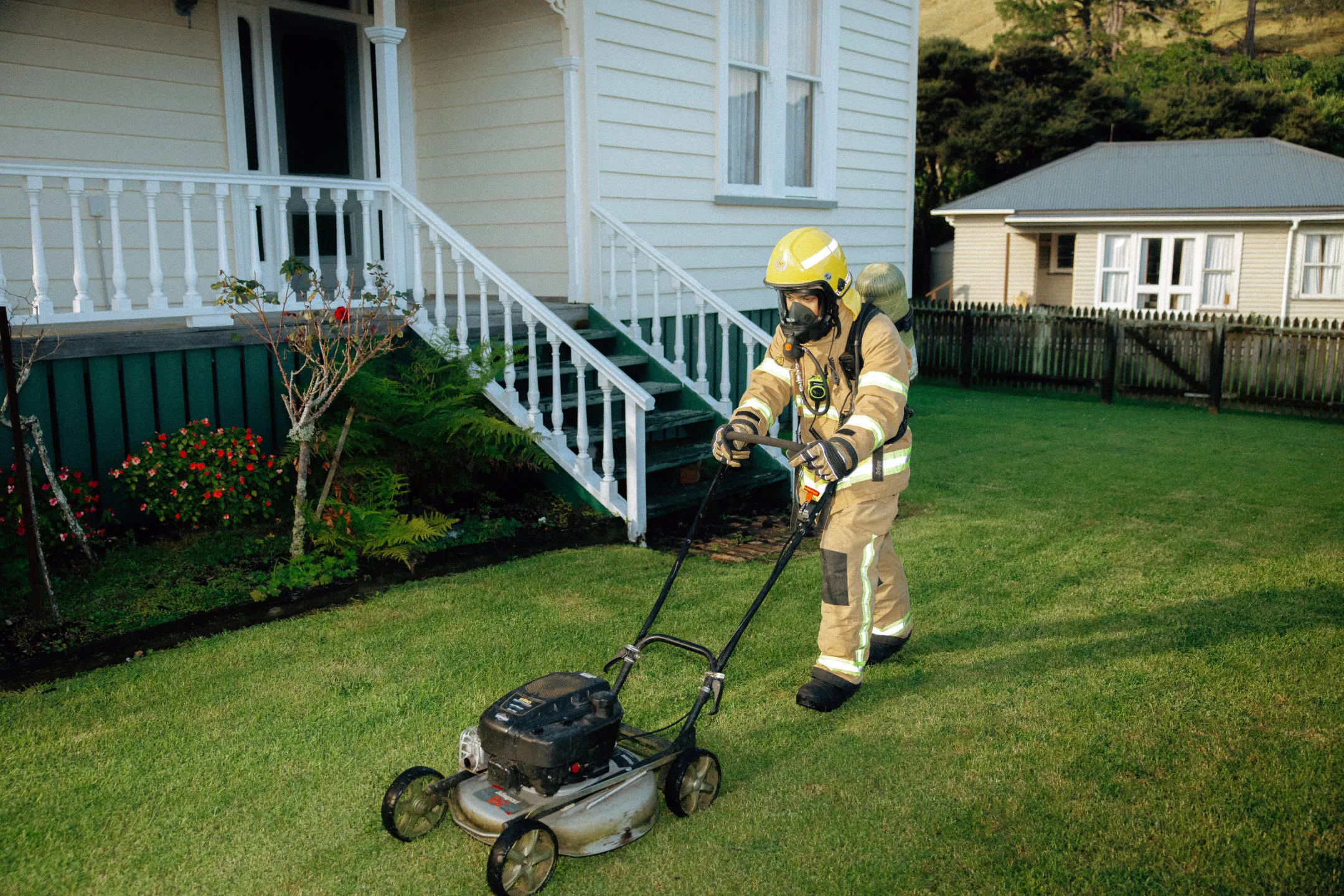 The Lawn Brigade crew mowing a Hokianga lawn in their fire brigade gear